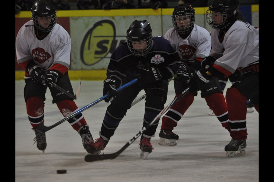 Estevan Mustangs forward Morgan Kjersem tries to deke through three Weyburn Blizzards skaters at the inaugural SSFHL atom championship final in the Civic Auditorium on Sunday.