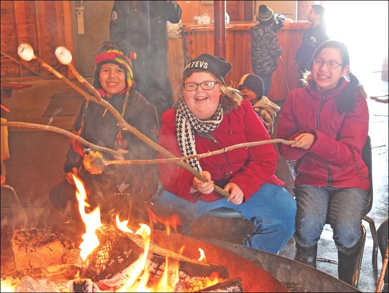 Friends Trinity Halcrow, 10, Tobie Pardoski, 11, and Louisa Bone, 11, roast marshmallows inside the Rotary Wheel.