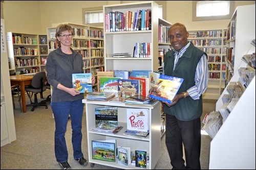 Head librarian for Battleford, Barb Beloin, and town councillor and library board member Gordon Yarde display a collection of children's books from across Canada, recently won by the Town of Battleford and donated to the library. Photos by Jayne Foster
