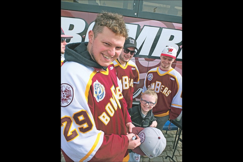 Flin Flon Bombers goalie Zac Robidoux autographs Ethan Jones’ ballcap as the 10-year-old fan looks on. The Bombers signed autographs and held photo-ops with fans on Main Street on Wednesday afternoon, a day before leaving for North Battleford to start their semi-final series against the North Stars. Also pictured are Bombers blueliners Curtis Roach (left) and Mason Etter.