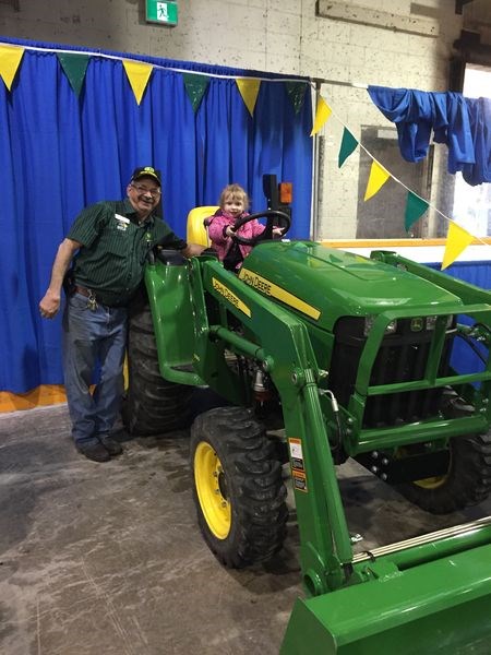Adley Ward and her grandfather Jim Ward posed for a picture with a Maple Farm Equipment tractor at the Spring Expo trade show on April 15 and 16.