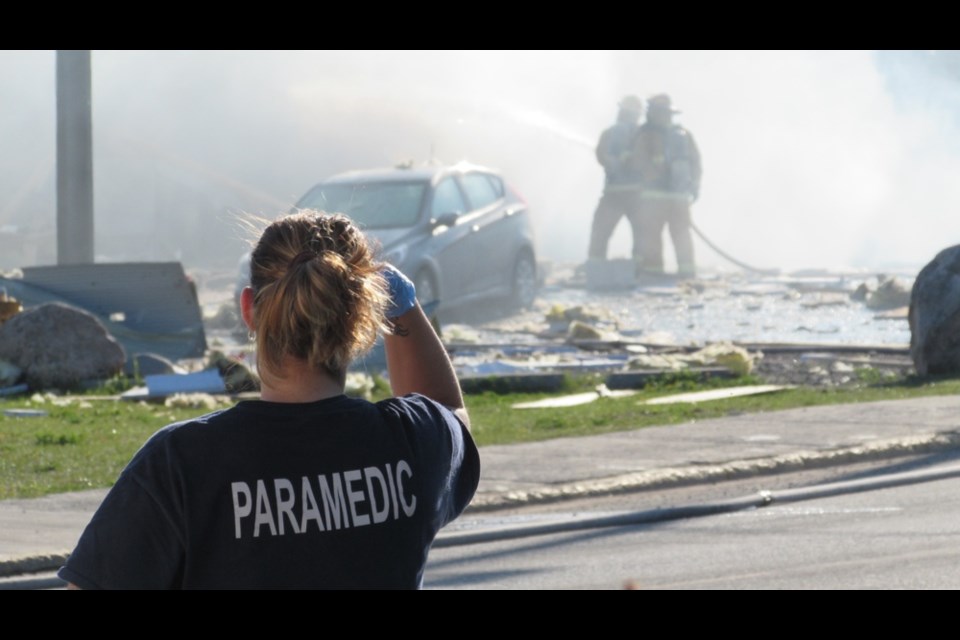 A paramedic watches firefighters douse the garage Wednesday morning. (Click arrows to scroll through photos).