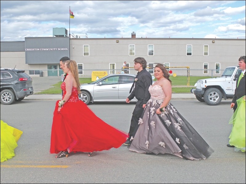 Kylee Andersen smiles as she and her fellow graduates march past their school.
