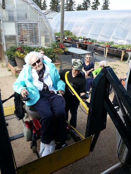 Helen Derwores, a resident of the KDNH, was photographed boarding the Handi-bus to go back to Kamsack. Operating the lift controls was Sid Novitski, the bus driver.