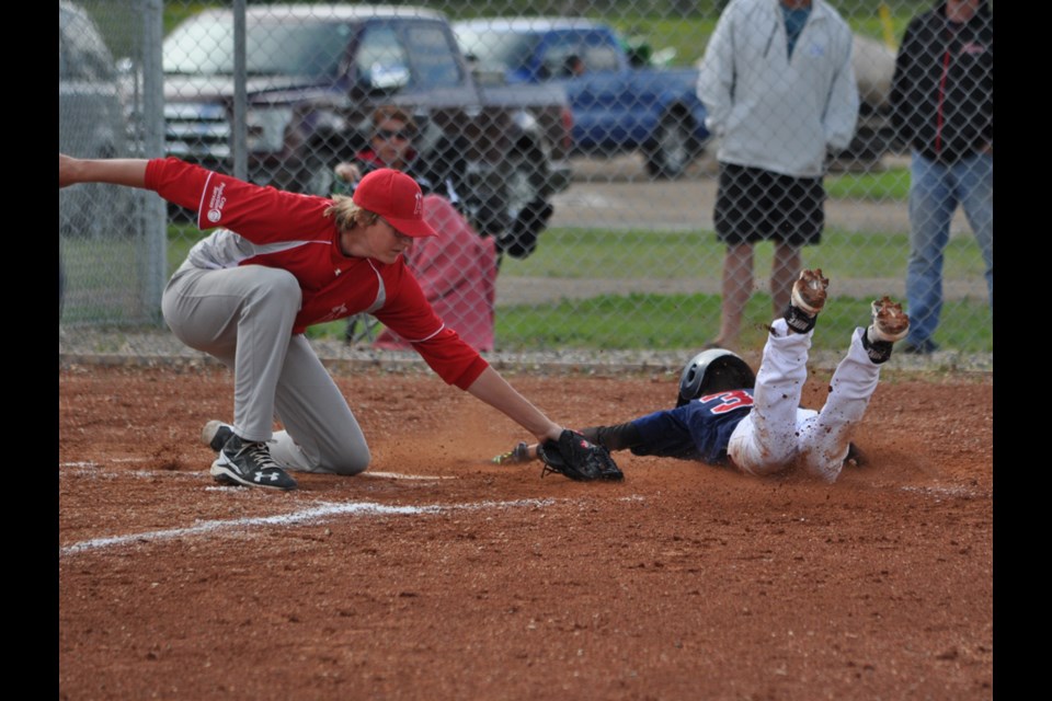 A's pitcher Justin VanAchte tags out Indians baserunner Nolan Klein as he dives onto home base.