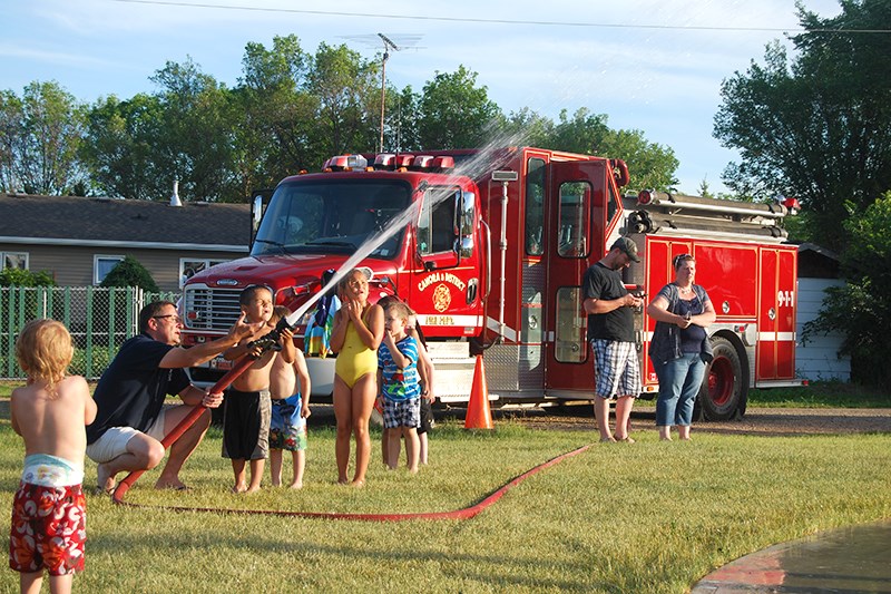 Eric Sweeney demonstrated the use of the fire hose for excited children at the Canora Soccer Club’s windup party on June 23.