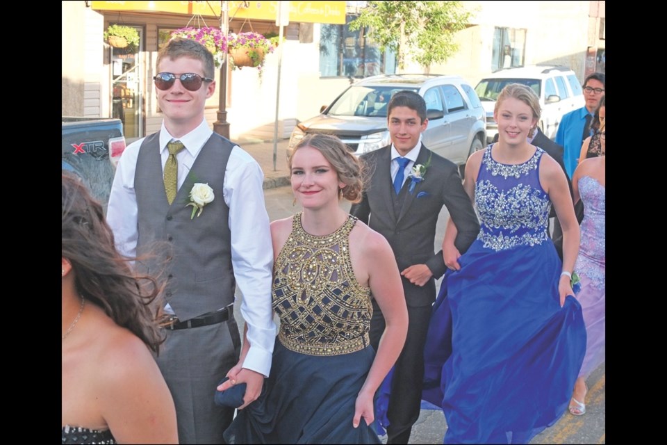 Nick Novosel, graduate Ariel Henderson, Mark Linnick and graduate Taylor Oliynyk march down Main Street.