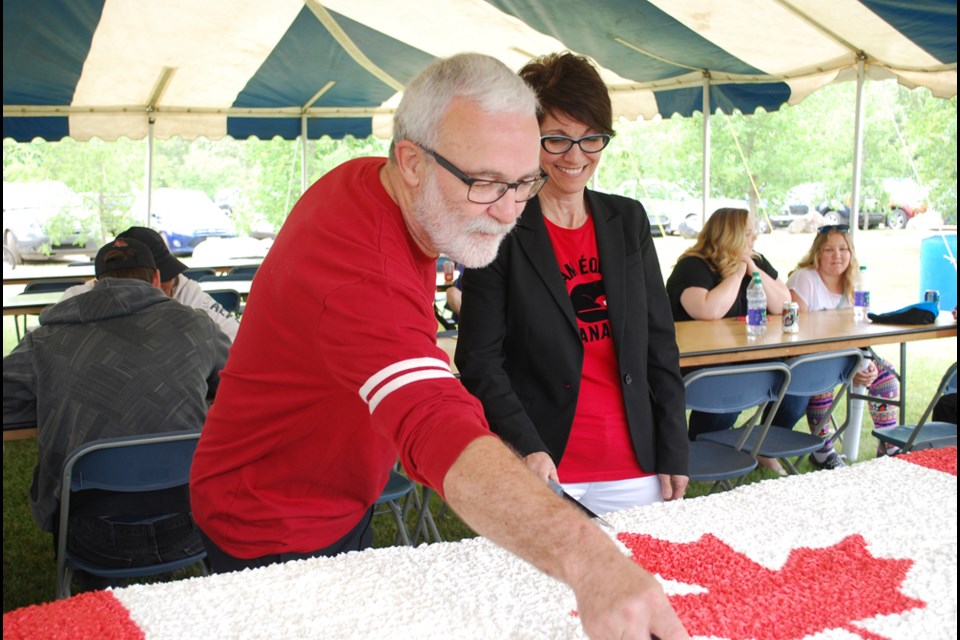 Mayor Malcolm Eaton and Member of Parliament for Carlton Trail–Eagle Creek, Kelly Block, cut the Canada Day cake at the Canada Day celebration at Water Ridge Park on Jul. 1. See page 7 for more pictures from the celebration. photo by Becky Zimmer