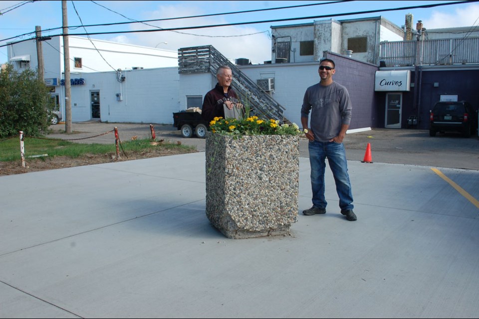 BID chairman Barry O’Handley and Harley Lafontaine chat as they stand beside the planter, which is one of two designated areas for parking motorcycles in the city’s renewed parking lot in the central part of the city.