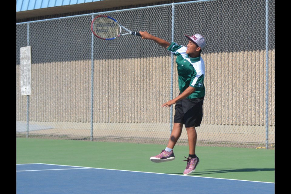 Clark Cabiluna contributing to Team South East's win in male doubles tennis, leaps into a serve.