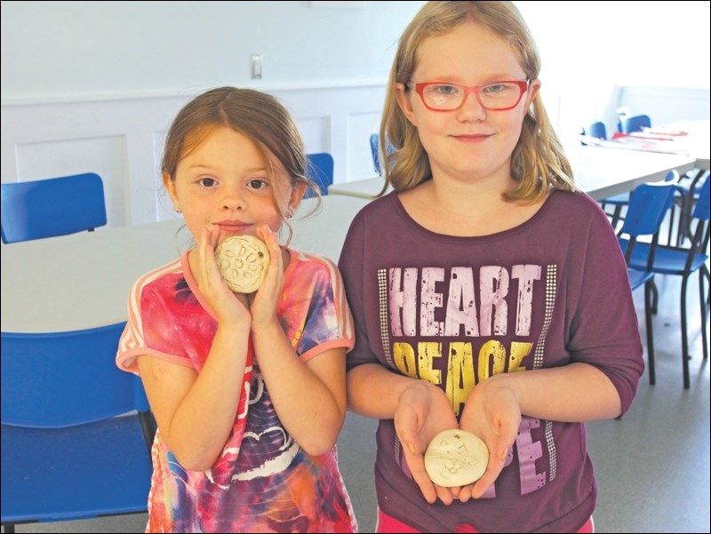 Rebecca Moore and Alexa Thorimbert show off medals crafted from clay, one of many activities local kids tried out during the Olympics-themed Camp Soleil.