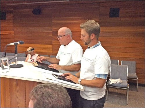 Rob Rongve and David Schell present to city council about the Saskatchewan Winter Games. A Games t-shirt was presented to councillors and to Mayor Ian Hamilton on Monday. Photos by John Cairns
