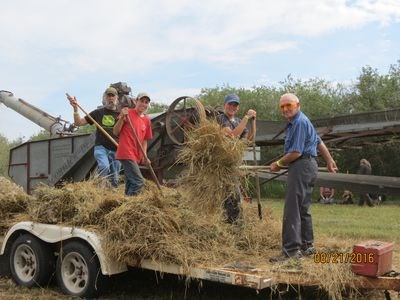 John Oystryk of Canora, right, threw a sheaf into the threshing machine. He used a similar machine when he was 17 years old, and he is now 92.
