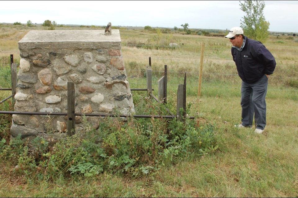 Don Cowan reads the inscription on a family cairn at the far end of Estevan’s first cemetery.