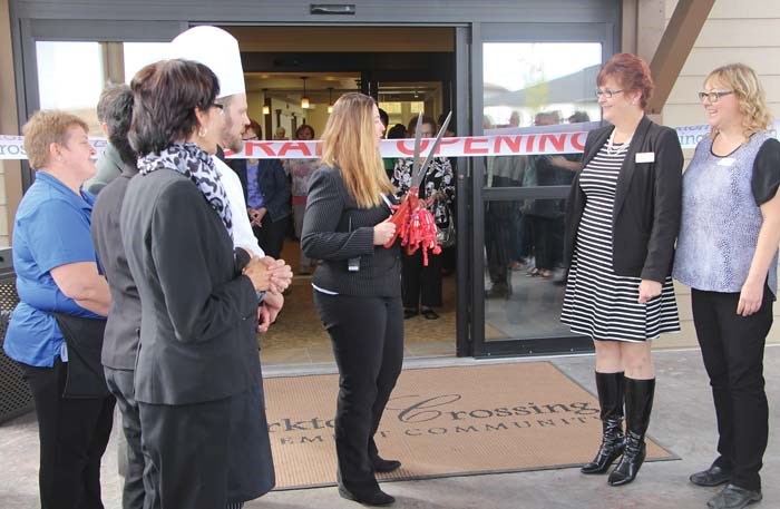 Heather Martin, Executive Director of Yorkton Crossing, cuts the ribbon at the opening of the new retirement community with the rest of the staff.