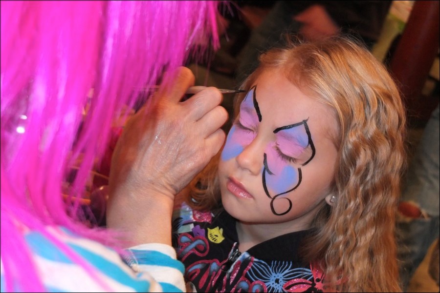 Paisley Durkee, 6, has her face painted by Puff the Clown.