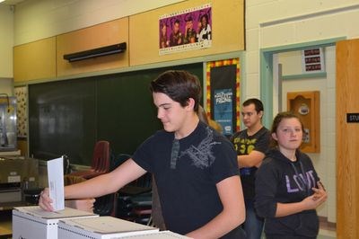 Alden Baron, left, placed his vote for the mock municipal elections for Student Vote Day, as Ian High and Emma Neratini waited for their turn.