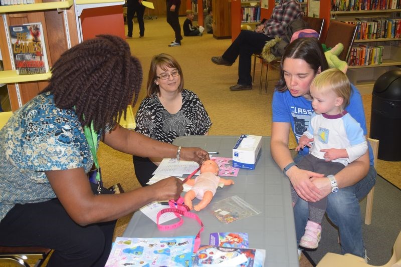 The first stop that children made during the Teddy Bear Clinic in Kamsack last week was to a reception desk where Mobola Ogunbiyi, left, the instructor of a university nursing course at Parkland College in Yorkton, took information about the children and their teddy bears or dolls that they had brought with them. Esmie Sumner, who attended with her mother Louise, had her doll measured by Ogunbiyi. At centre was Kim Gelowitz, the director of the Yorkton Family Resource Centre.