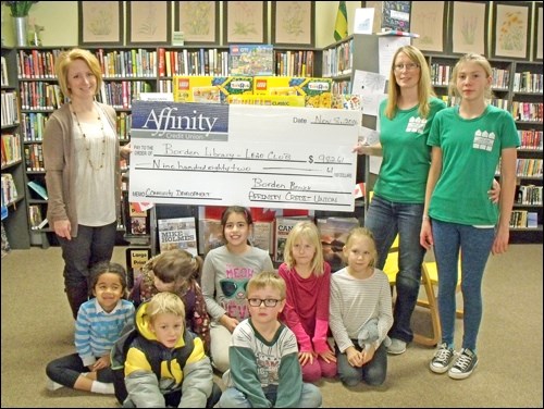 Lynette Schmidt from Affinity Credit Union presents a cheque to Rhonda Funk of Borden Library for the Lego Club. Sadie Funk and some Lego builders are in the photo.