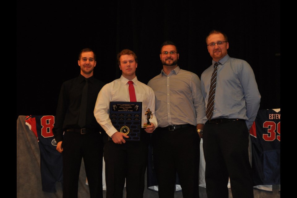 Elecs quarterback Andrew Kehler is presented with the team's MVP award by coaches, from Braiden Senchuk, Ryan Jutras and Mark Schott.