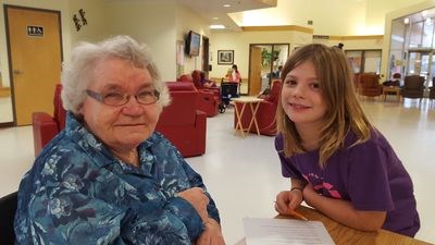 Tess Covlin, right, enjoyed listening to Rosie Yurfiw's story on November 22 when the Preeceville School Grade 3 class visited with the long term care residents in Preeceville.