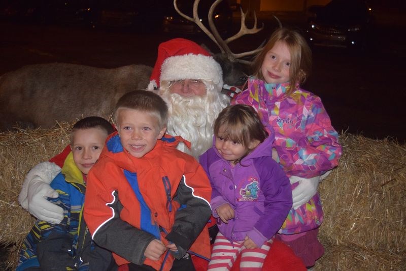 Santa Claus was in Kamsack on Friday to attend the Moonlight Madness promotion and star in the Santa Claus parade along with two of his reindeer. Following the parade, everyone had opportunity to have a photo taken with Santa, including, from left, Theo, Torran, Tayla and Takara Maciborski of Kamsack. At back was one of his reindeer.