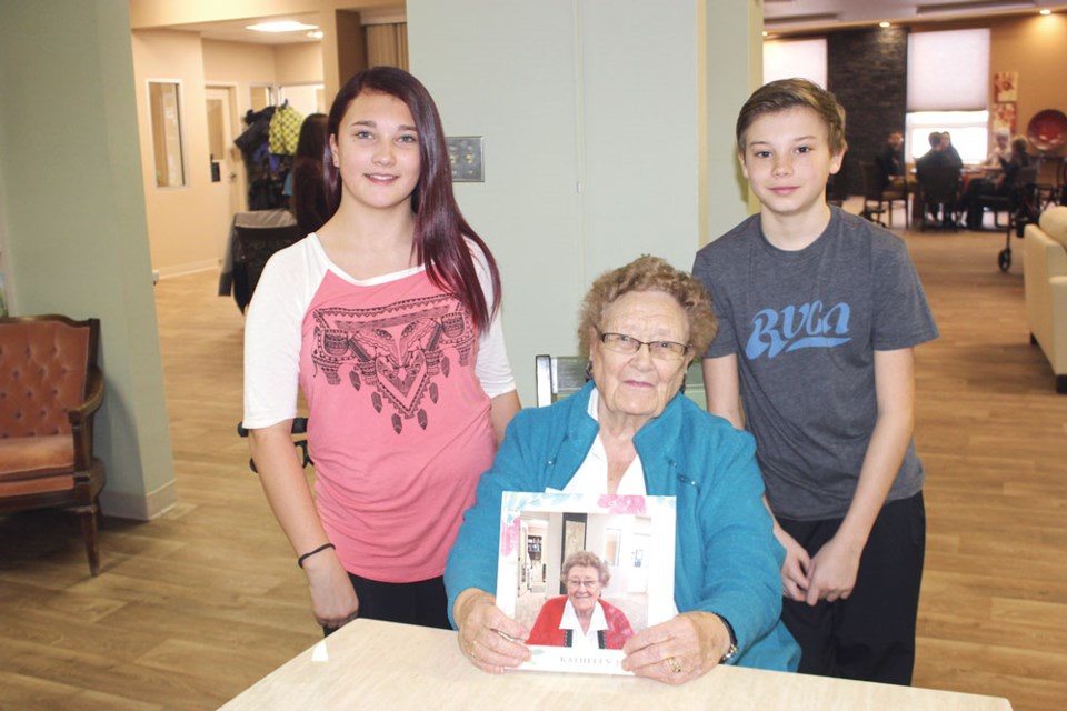 Kathleen Johnson, middle, was happy to receive her legacy book from Lyssa Strilaeff, left, and Kyler Gingras.