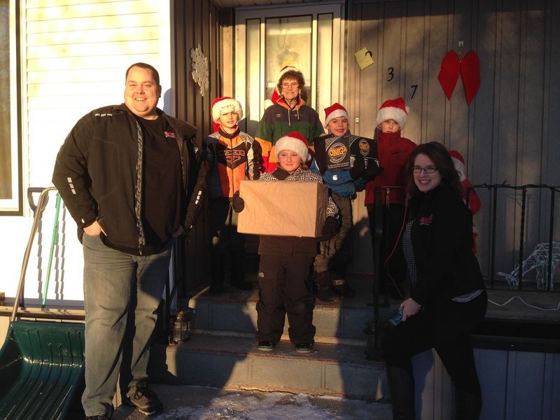 After having telephoned Santa Claus to tell him what they had wanted for Christmas, the group of children being tended by Ardis Irvine of Kamsack received gifts brought to them by personalities at GX94/FOX FM on December 9. In return the children sang carols for their guests and presented them with a box of chocolates. From left are: Danny Ismond of the radio station, Levon Clark, Ardis Irvine, Cage Clark who had won a laptop in the same promotion last year, Timothy Holoboff, Meesha Romaniuk and Tonya Cherry, also of the radio station.