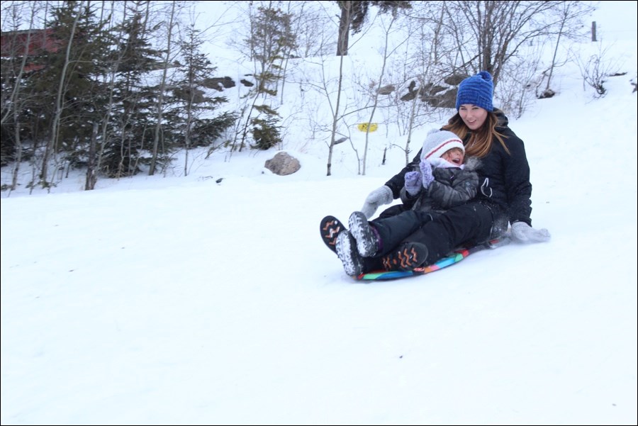 Sarah Phair and daughter Zoey glide down the sliding hill near École McIsaac School on Wednesday afternoon. Many area residents took advantage of mild weather and the Christmas break to enjoy time outside this week.