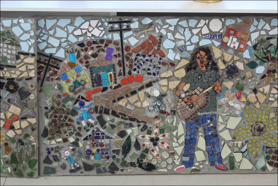 One scene from the mosaic features a musician playing in front of houses, twisting streets and sewer boxes. Many of the houses were built by local schoolchildren.