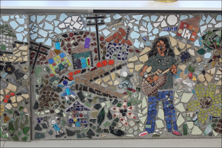 One scene from the mosaic features a musician playing in front of houses, twisting streets and sewer boxes. Many of the houses were built by local schoolchildren.