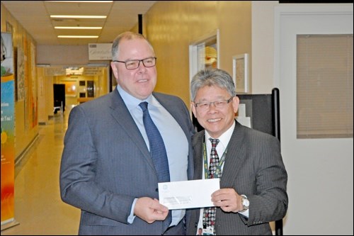 Prairie North CEO David Fan accepts a cheque from Scott Livingstone of the Saskatchewan Cancer Agency.