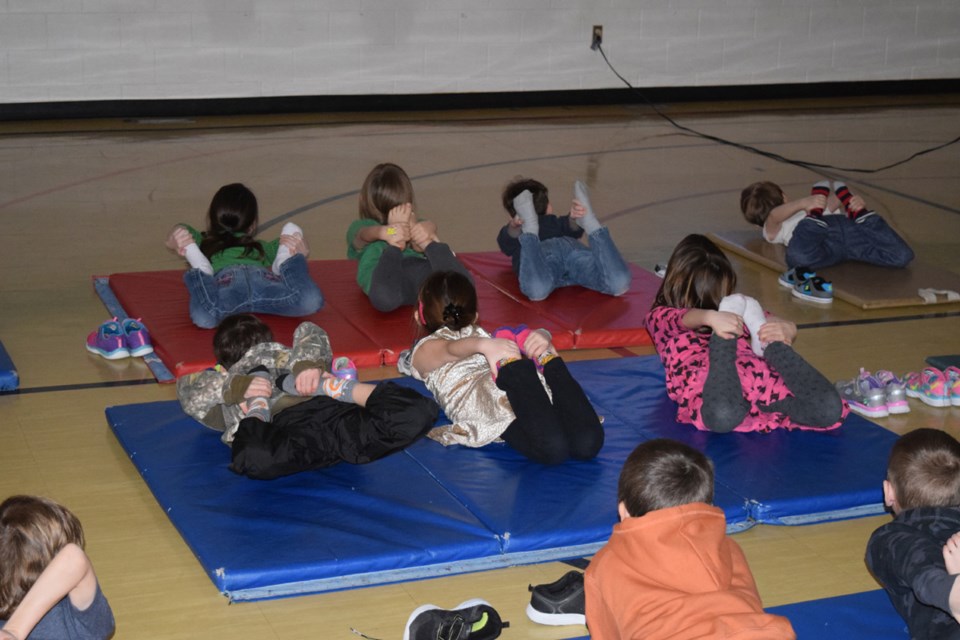 Kindergarten to Grade 2 students practiced a variety of yoga poses, such as the bow pose...