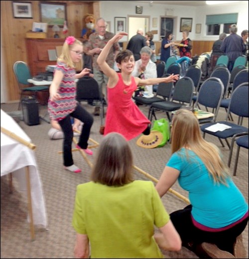 Ava Gansuage (flower in hair) and Hannah Konopelski (dancing) under the guidance of Trudy Jensen and Tanya Gansuage, learning to do the bamboo dance.