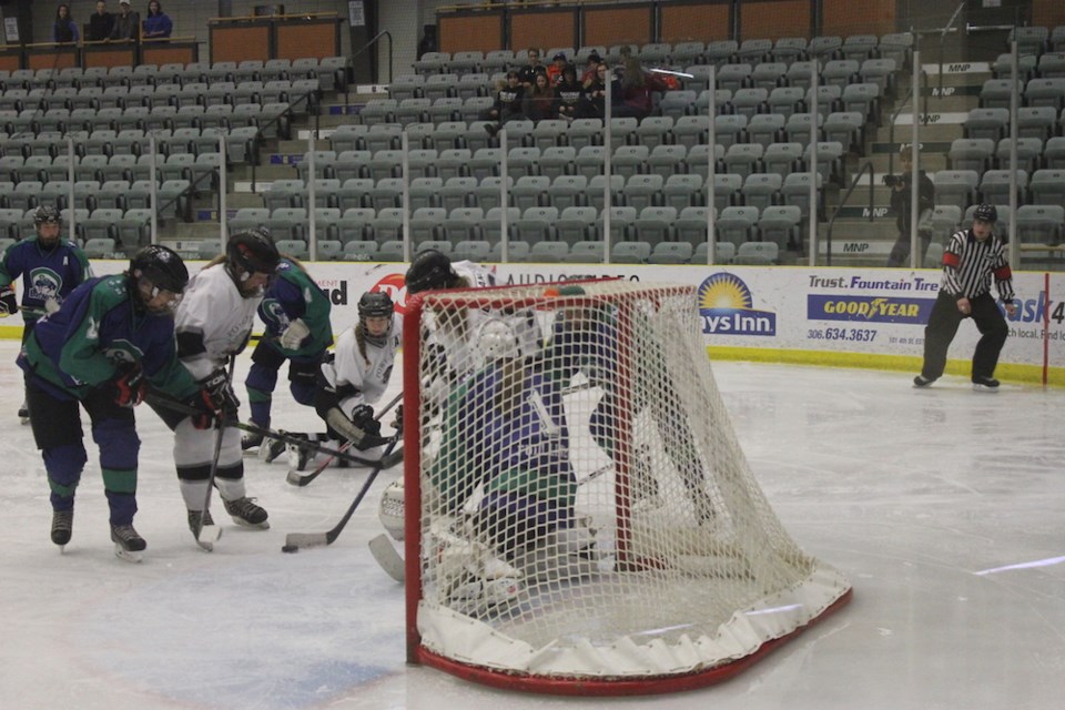 Swift Current goaltender Cheyenne Jamieson makes a save with Estevan and Swift Current players in fr