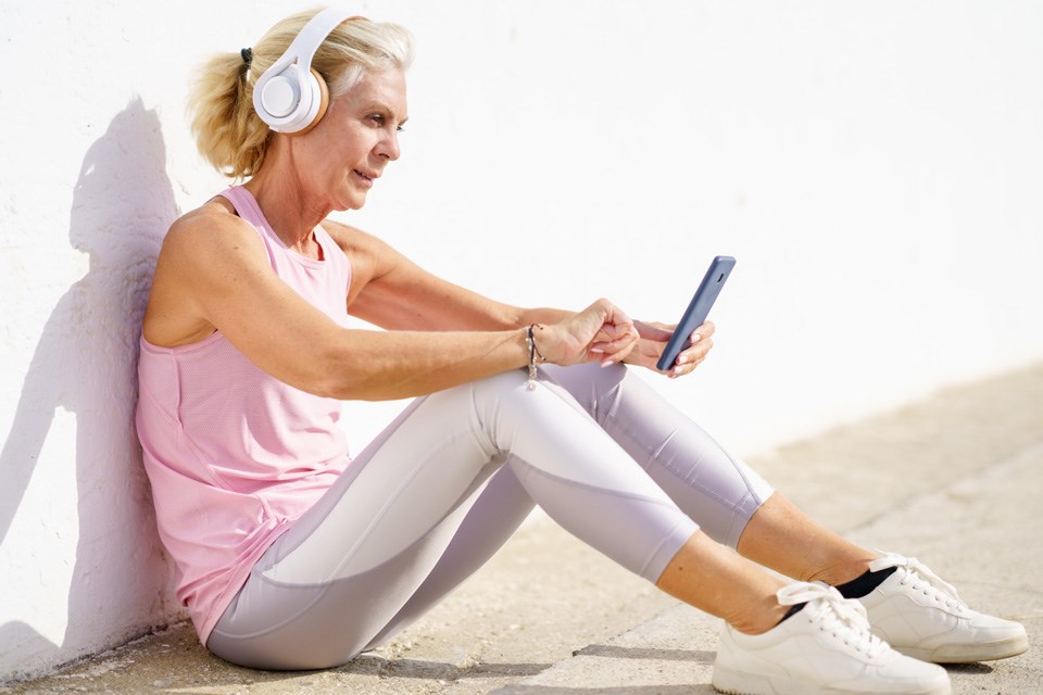 A mature female takes a break to check a fitness app on her smartphone as part of her healthy living routine.