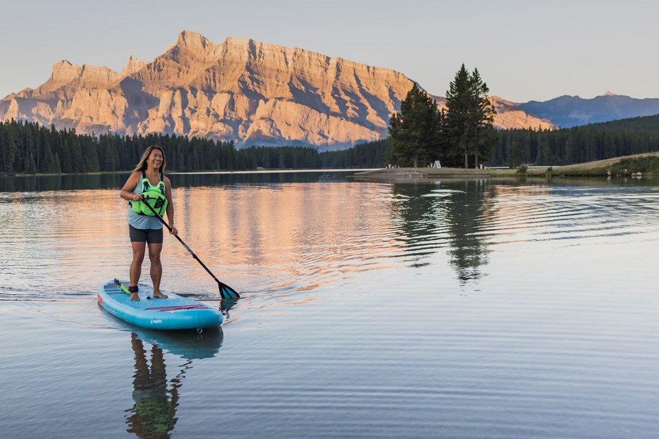 Two Jack: Awoman paddleboarding on Two Jack Lake as the sun hits the mountain face behind her / Banff & Lake Louise Tourism
