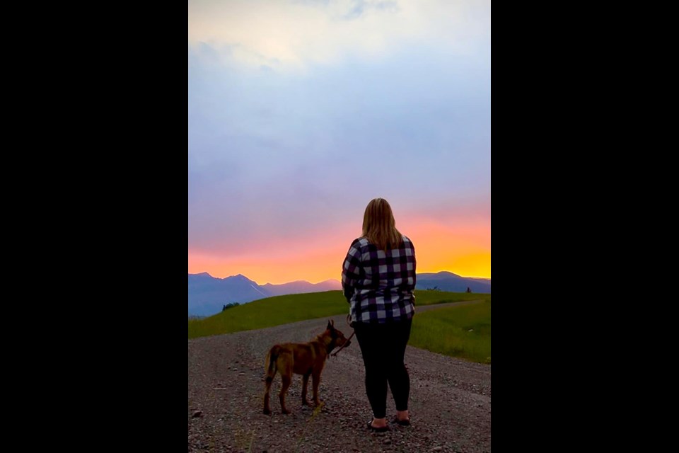 A woman walks her dog in front of a gorgeous sunset at Ya Ha Tinda Ranch. / Ya Ha Tinda Ranch | Facebook