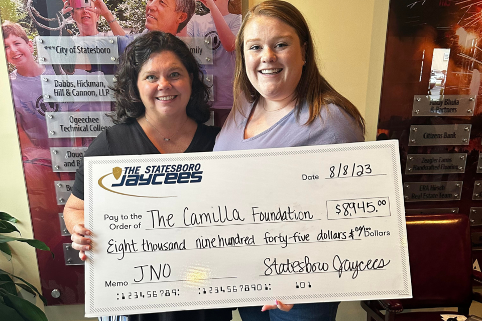 Bailey Catrabone-Brinson (right) presents a check to April Miller of The Camilla Foundation for a portion of the proceeds from the 2023  Jaycees Nite Out event.