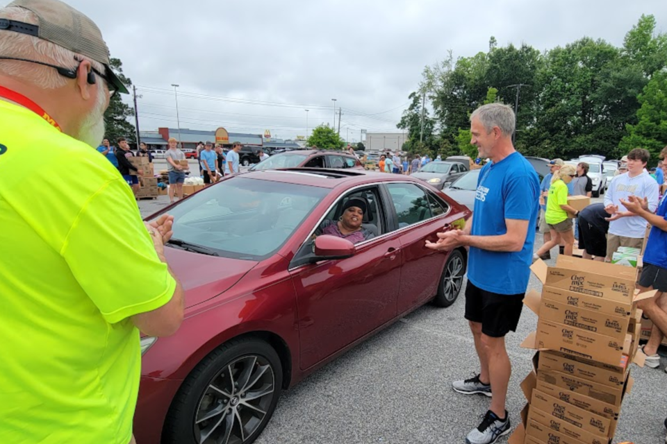 Don Poe (L) watches as Chris Dove (R) hands Marsha Fulton a $250 Food Lion gift card