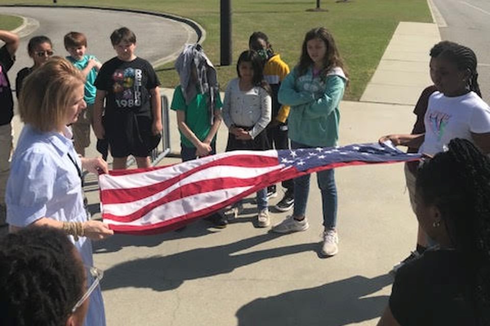 Dawn Beck teaches a group of students about proper flag protocol before they begin their daily flag duties at Mill Creek Elementary School.
