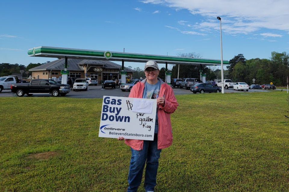 Believers Church member Stephanie Stills holding sign promoting gas buy down