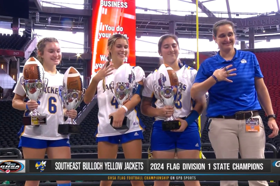 SEB wins GHSA Division One State Championship and receives trophy by SEB Yellow Jacket Seniors and head coach Marci Cochran. (Pictured L to R: Jaydyn WIlliams, Jaci Kitchings, Isabelle Cruz, Marci Cochran)