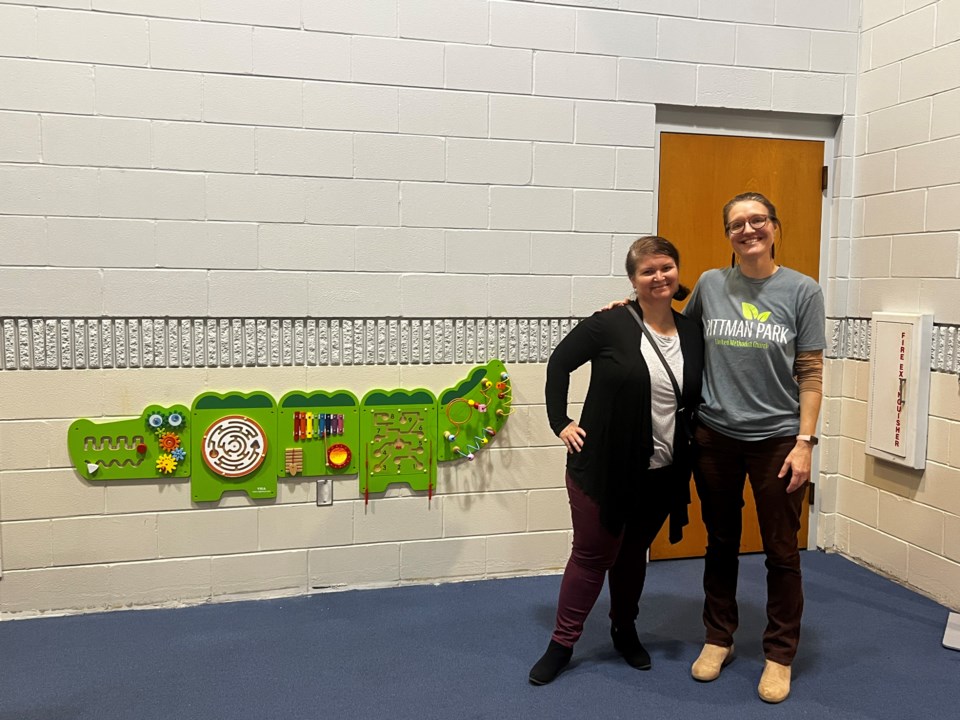 Pittman Park UMC Children's Director Megan Hopkins and church congregation member Michele Martin stand beside the church's alligator themed busy board.