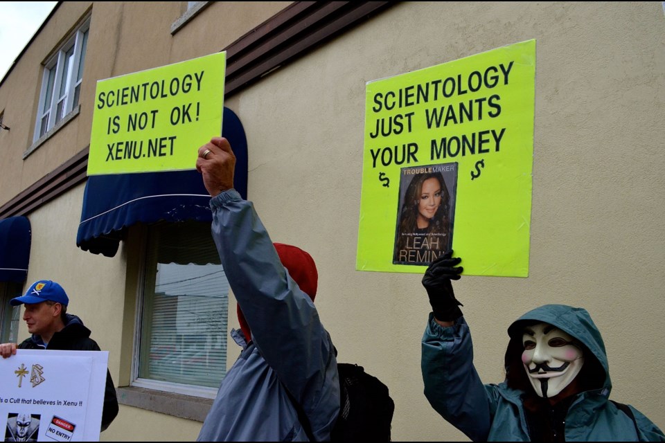 Masked protesters gather outside new Scientology office in Downtown