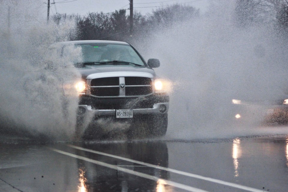 A car drives through a water puddle on Stone Road. Anam Khan/GuelphToday