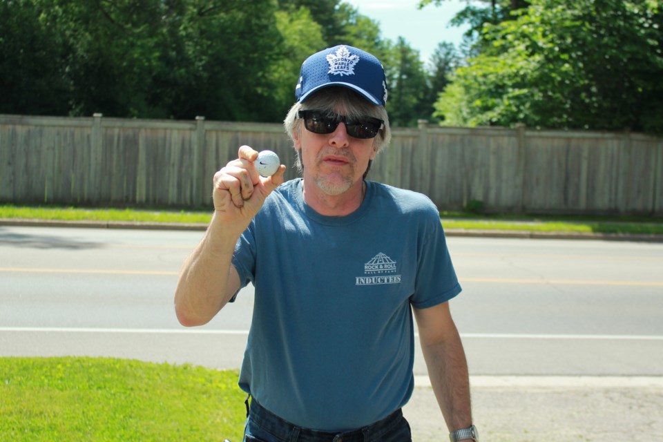 Dave Ostyn stands on his driveway  with his back towards the Guelph Country Club fence holding the golf ball he found on his property. Anam Khan/GuelphToday