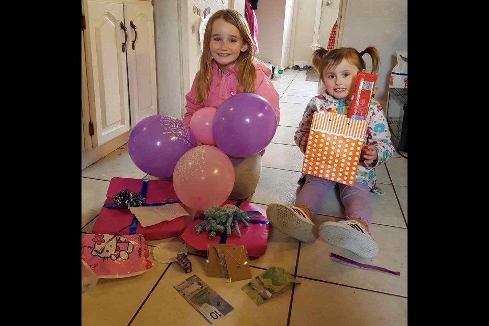 Hannah and Heidi sit in front of birthday presents they received from community members. Supplied photo