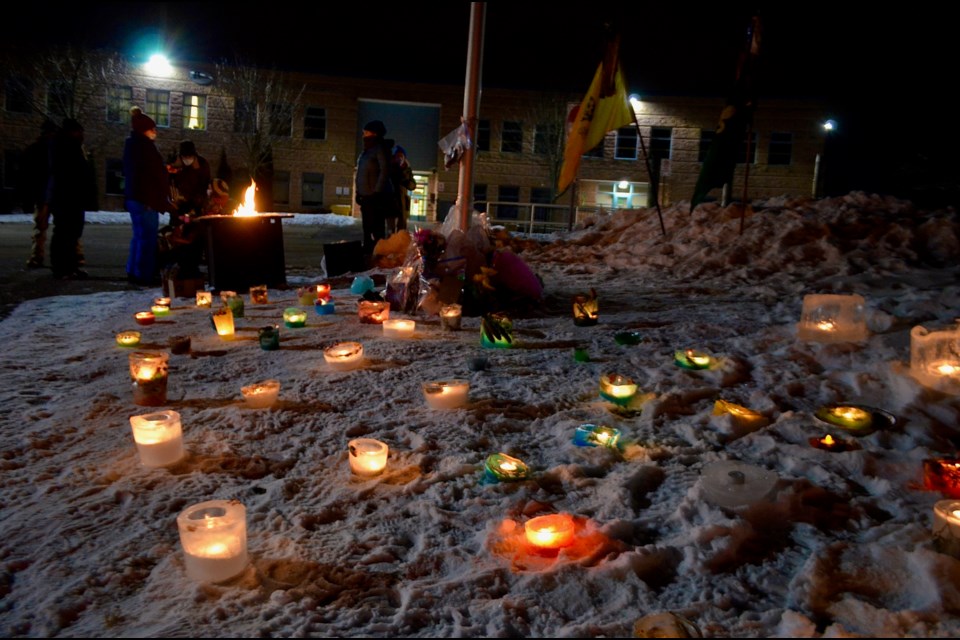 The community gathers safely at a candlelit memorial for Evan and Amanda Lodge at Taylor Evans Public School Friday evening.