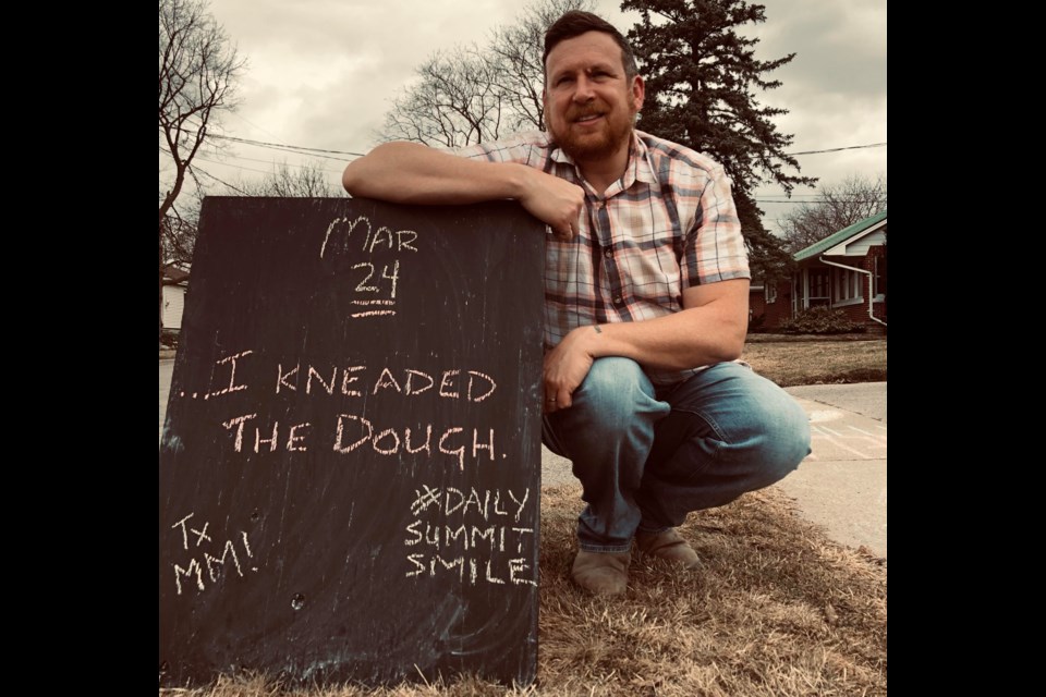Mark Hallman sits beside a sandwich board in front of his home on Wedneday with the answer to the dad joke of the day. Supplied photo